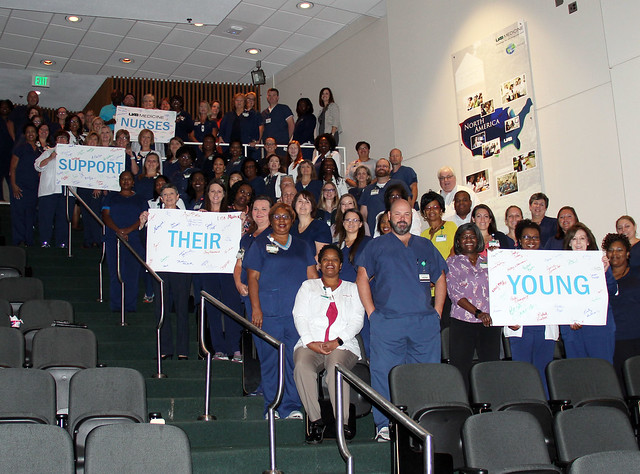 Nurses in auditorium holding posters that say "Nurses Support Their Young"