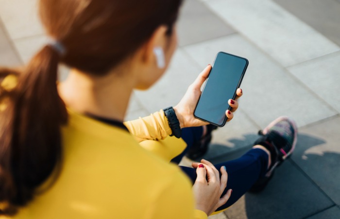 Female runner sitting down and looking at her phone