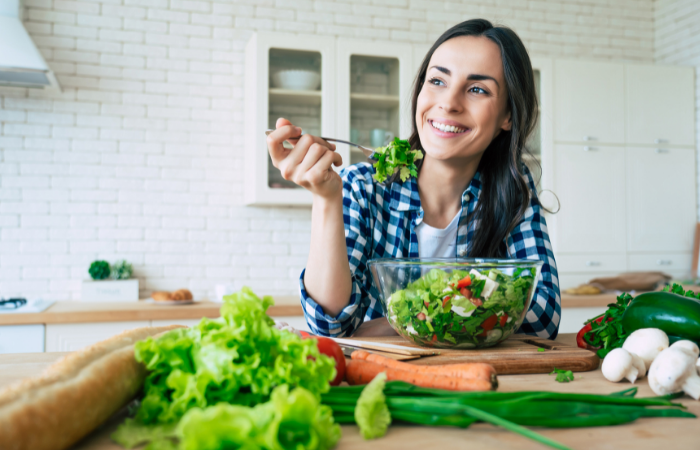 woman smiling while managing portion sizes of salad to maintain a healthy diet