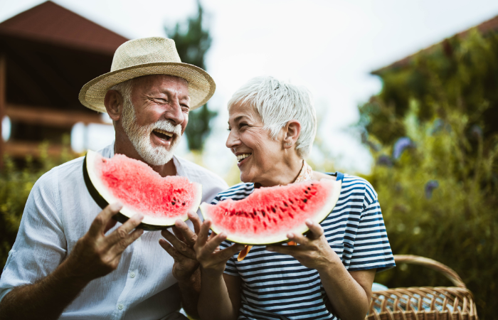 Elderly couple smiling and enjoying eating fresh watermelon