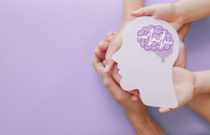 hands holding cutout of head showing brain activity