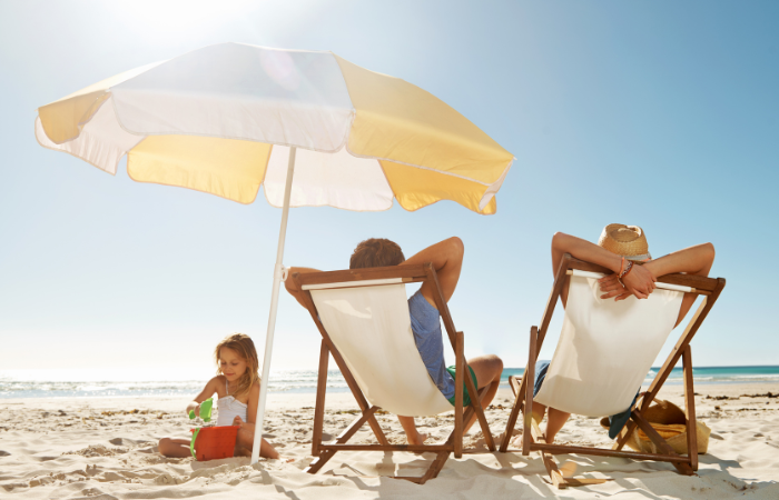 Mother and father relaxing on the beach while daughter plays in the sand