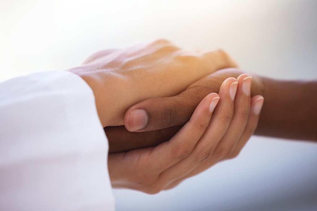 Shot of an unrecognizable doctor holding hands with her patient during a consultation