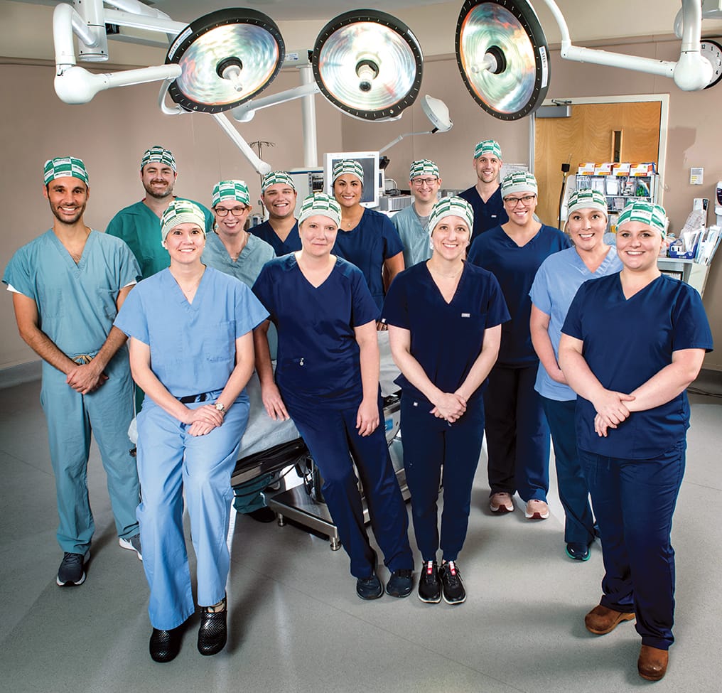 Group photo of medical professionals in blue scrubs and green and white head coverings