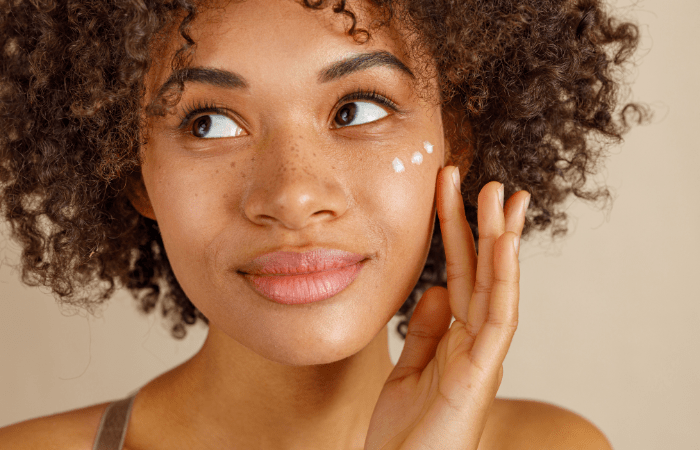 African American female applying moisturizer to her face