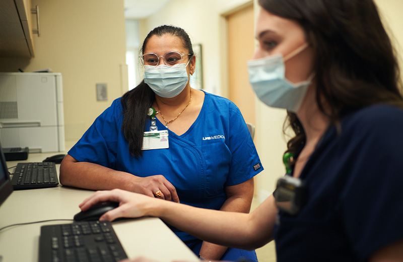 Two female medical professionals working at a computer together