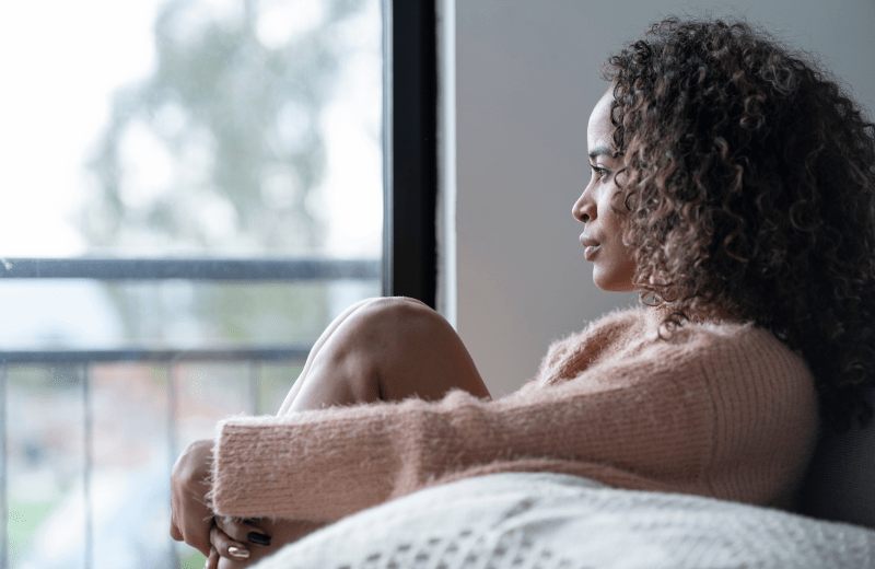 African American female sitting and looking out her window