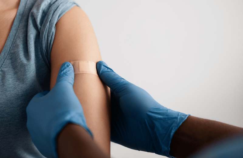 Nurse placing bandaid on a patient's arm after patient receives shot