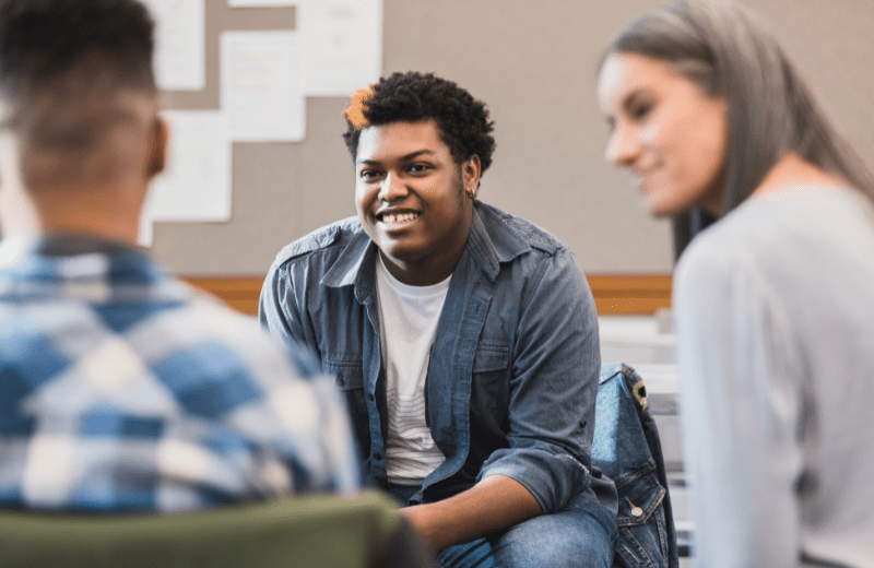 Group of people sitting in a circle with the focus on an African American male