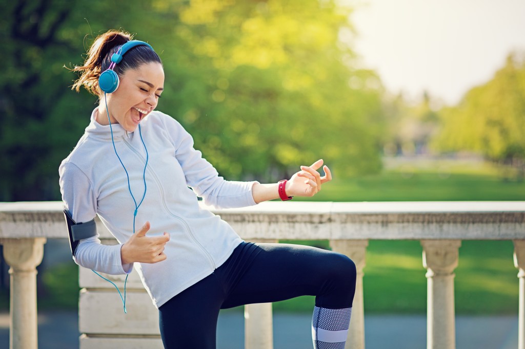 Female runner is pretending to play the guitar while listening to her favorite song